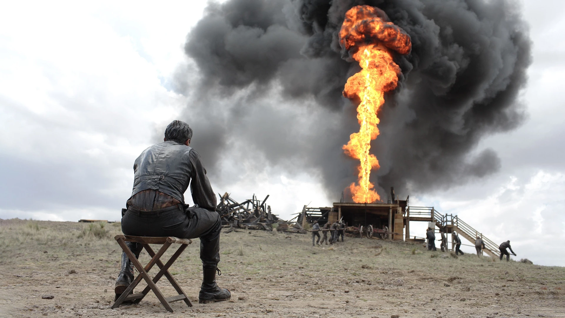 Daniel Plainview stands defiantly on a desolate oil field, a striking figure against a rugged landscape, symbolizing ambition and isolation.
