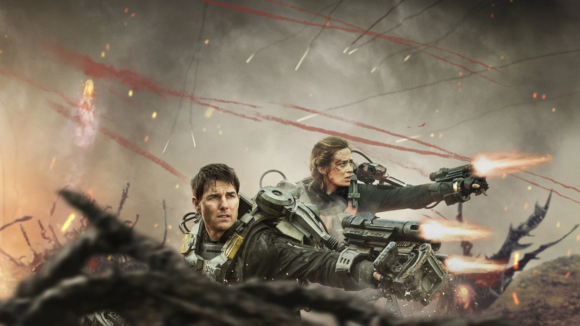 Tom Cruise and Emily Blunt in battle armor, looking determined amidst futuristic wreckage